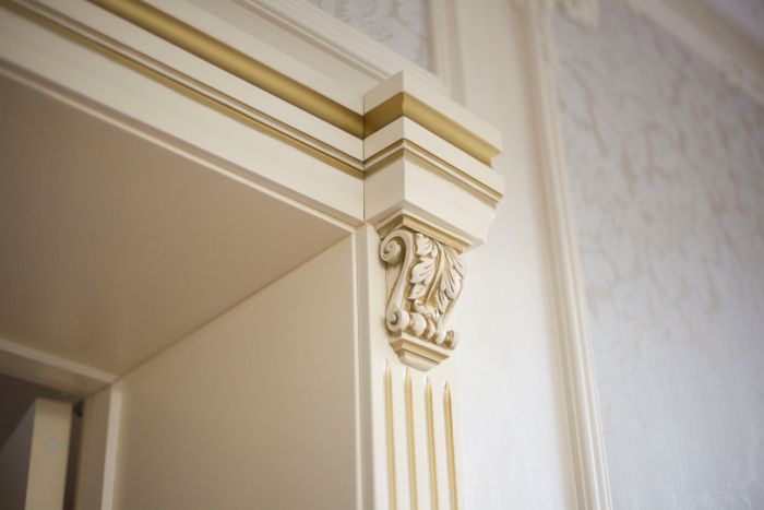 Ornamental crown moulding and corbel detail being fitted around a doorway