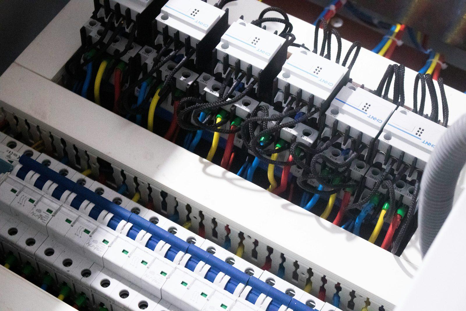 Open electrical distribution panel with color-coded wiring connected to circuit breakers