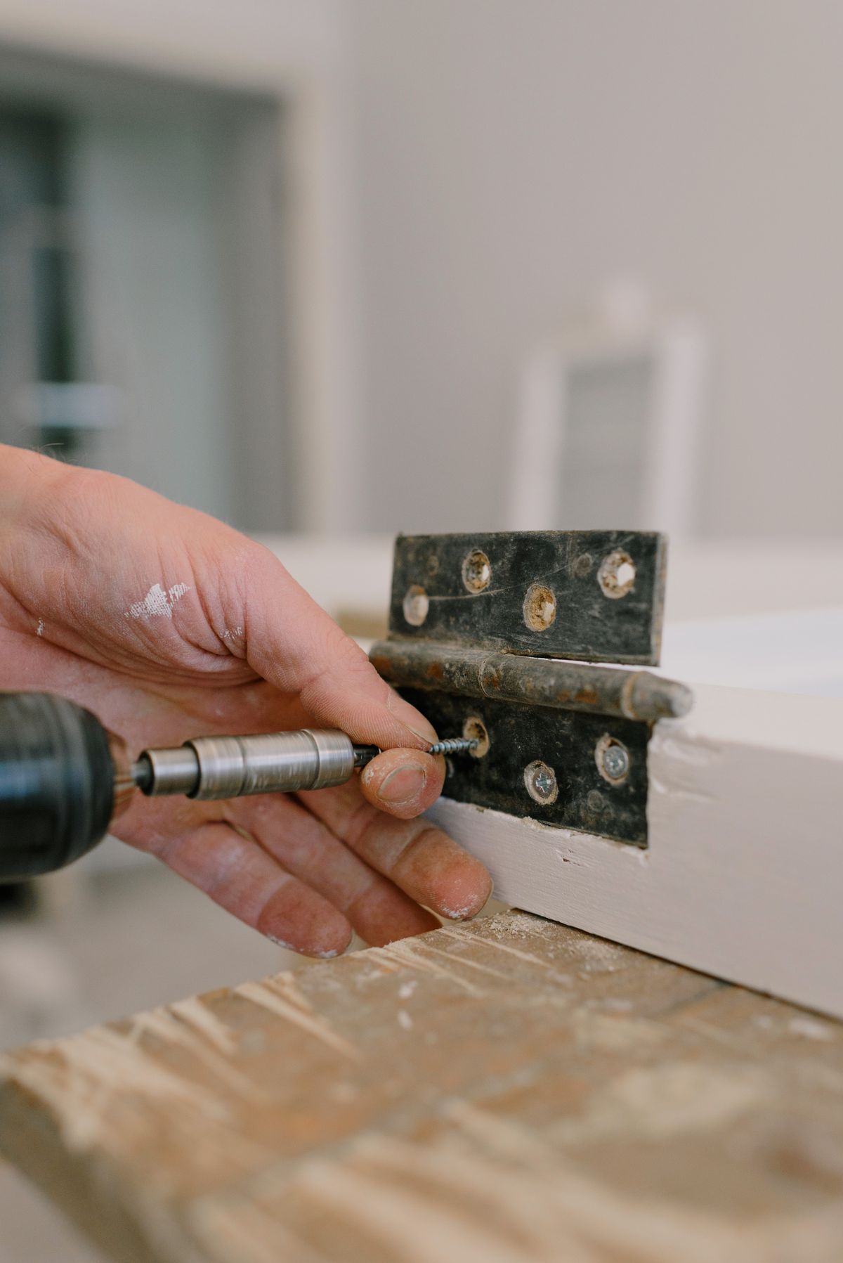 Hand fitting a door hinge with a screwdriver during final finishing work
