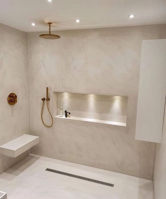 Marble shower with a warm-lit niche shelf and linear floor drain
