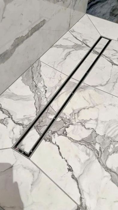 Long linear floor drain set into a veined marble floor