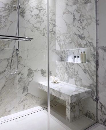 Styled marble shower with folded towels and bath amenities