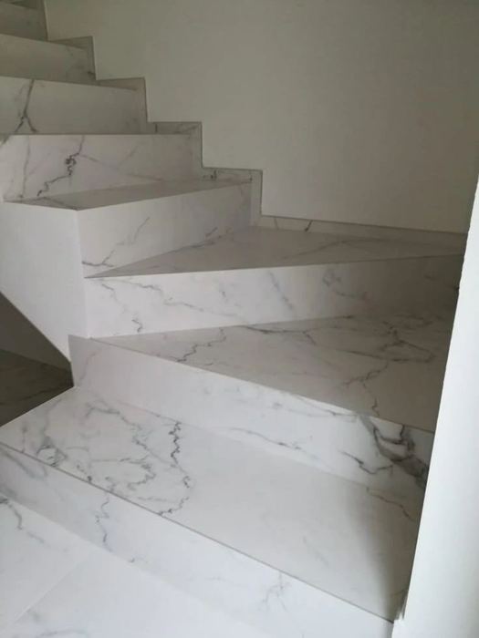 Sculptural glossy white marble winding staircase, an example of Nexo's tiling and stone work